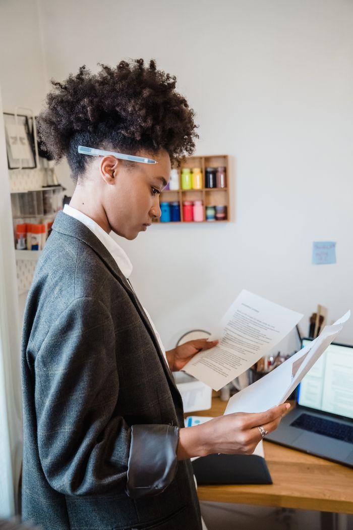 heros-img Businesswoman in a suit reviews paperwork at her desk with focus and determination.
